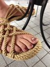 Person wears Nomadic State Rope Sandals in Camel on tile floor
