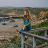 sitting on a fence at a beach wearing Lems Chillum Spruce and matching puffy jacket