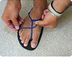 A person adjusts and customizes the royal blue lacing on their Xero Barefoot Shoe