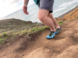 person walking up an inclined trail with shoreline in background, wearing Aqua X Sport in Surf