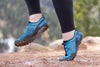 Feet wearing Aqua X Sport in women's sizing surf jump joyfully on a muddy dirt trail