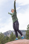 Woman standing on top of a rocky hill, wearing Aqua X Sports