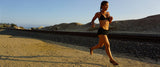 Woman running on sand wearing Earth Runners