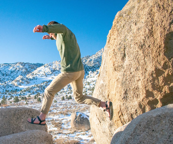 A man jumping across rocks in his Z-Trail EV Sandals