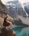 Man crouching at Lake Louise in Earth Runners