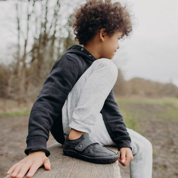 A child wearing Vivo Barefoot Primus School II Kids Velcro school uniform shoes Black Leather